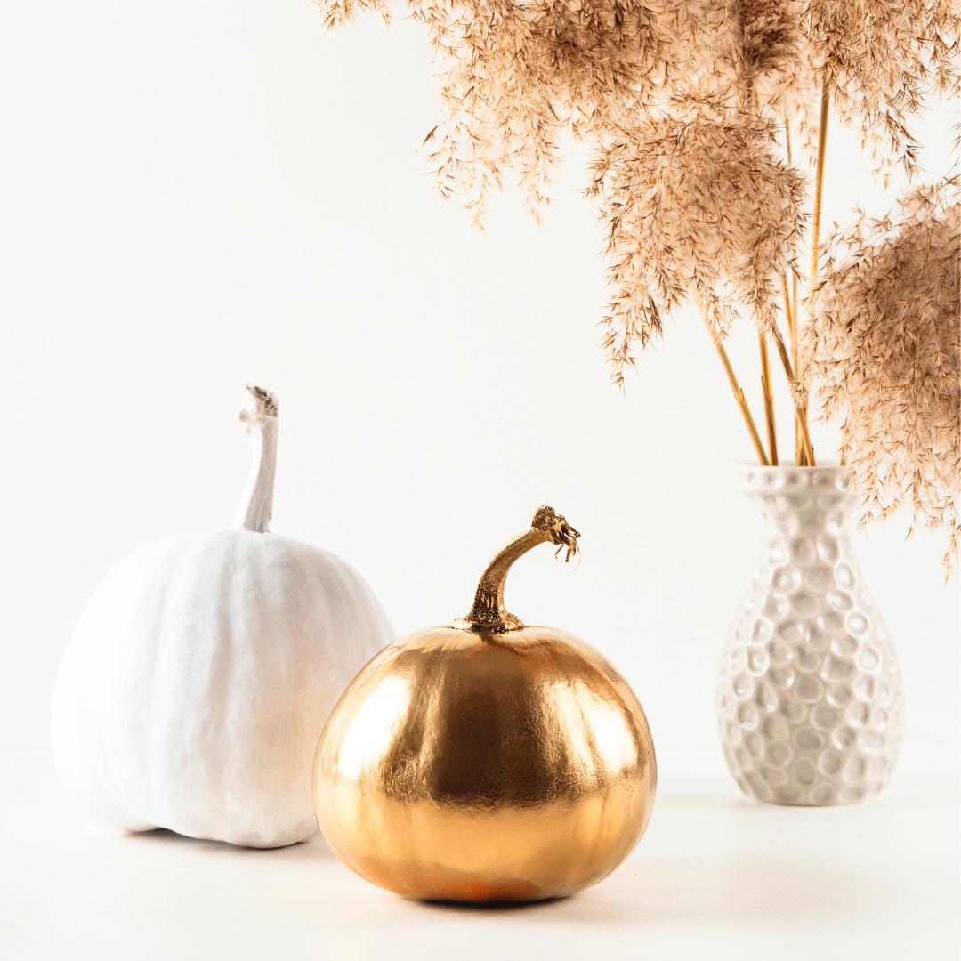 White and gold pumpkins next vase with pampas grass.