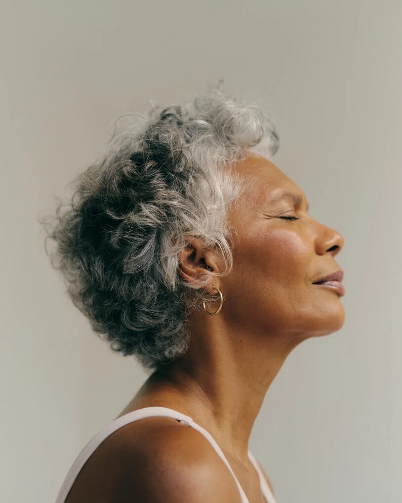 Woman relaxing with eyes closed after receiving skincare for deeper skin tones.